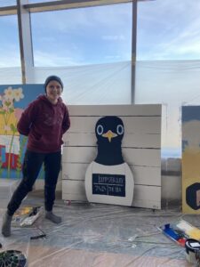 Young person standing in front of their artwork representing a sea gull which has been arrested for dumpster diving. 