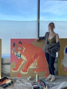 Young person standing in front of painting of a tiger 