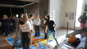 Íslenska: Ungmenni taka þátt í landakortsleik á gólfi, hlæja og skoða spjöld með upplýsingum um Evrópu. English: Young people take part in a European map floor game, laughing and reading info cards.