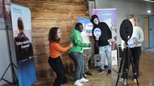 Íslenska: Ungmenni stilla sér upp fyrir myndatöku í ljósmyndabása á afmælishátíð Eurodesk. Þau halda á skiltum með ártölum og hlæja saman. English: Young people pose for a photo booth picture at the Eurodesk anniversary celebration, holding year signs and laughing together.
