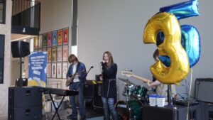 Íslenska: Hljómsveitin Kyrsa flytur tónlist á sviði með blöðrum sem mynda töluna 35 í forgrunni. English: The band Kyrsa performs live on stage with large number "35" balloons marking the celebration.